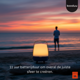 Person standing on a beach at sunset with a lit lantern and 'kooduu' branding.